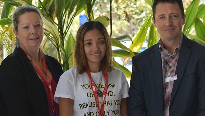 Three people standing in front of greenery, smiling