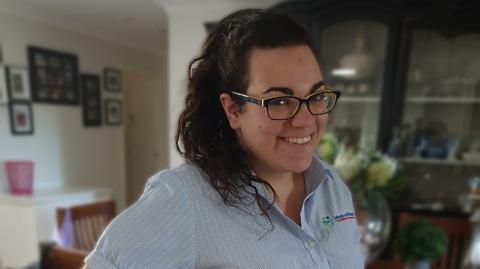 Sarah smiling at the camera. She is wearing glasses and her Meals on Wheels blouse.