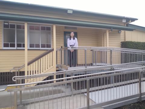 A woman standing in front of a building smiling at the camera